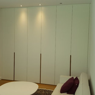 Modelo de vestidor unisex, actual, de tamaño medio, con armarios con paneles lisos, puertas de armario blancas, suelo laminado y suelo marrón