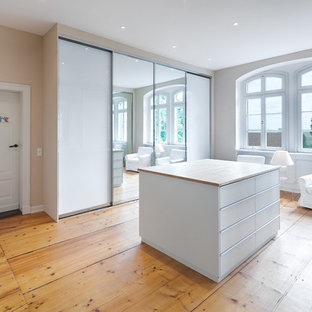 Neutrales, Großes Modernes Ankleidezimmer mit Ankleidebereich, Glasfronten, weißen Schränken, braunem Holzboden und braunem Boden in Hannover