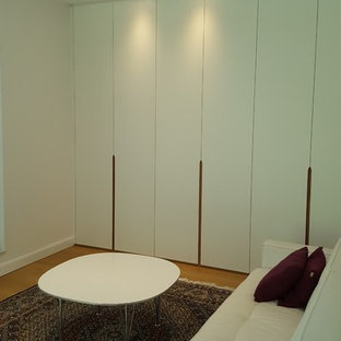 Immagine di uno spazio per vestirsi unisex minimal di medie dimensioni con ante lisce, ante bianche, pavimento in laminato e pavimento marrone