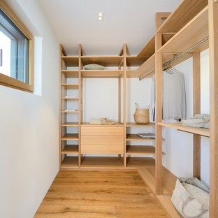 Ejemplo de armario vestidor unisex, nórdico, de tamaño medio, con armarios abiertos, suelo de madera oscura y puertas de armario beige