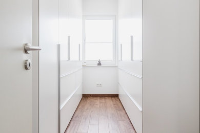 Kleines, Neutrales Modernes Ankleidezimmer mit Ankleidebereich, flächenbündigen Schrankfronten, weißen Schränken, dunklem Holzboden und braunem Boden in Frankfurt am Main