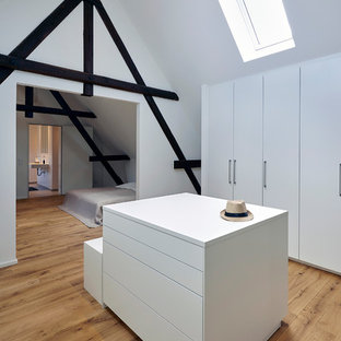 Neutraler, Großer Moderner Begehbarer Kleiderschrank mit flächenbündigen Schrankfronten, weißen Schränken, braunem Holzboden und braunem Boden in Köln