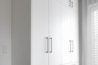 Foto de armario y vestidor unisex contemporáneo grande con armarios con paneles lisos, puertas de armario blancas, suelo de madera oscura y suelo marrón