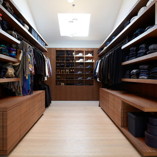 Diseño de armario vestidor unisex, moderno, de tamaño medio, con armarios abiertos, puertas de armario marrones y suelo de madera clara