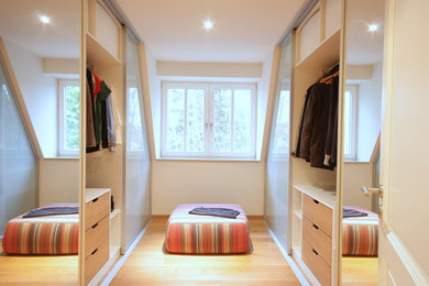Imagen de vestidor unisex contemporáneo de tamaño medio con armarios tipo vitrina y suelo de madera clara