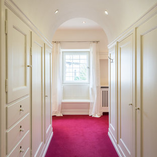 Exemple d'un placard dressing chic de taille moyenne pour une femme avec un placard avec porte à panneau encastré, des portes de placard blanches, moquette et un sol rose.