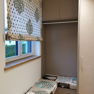 Modelo de vestidor nórdico, grande, con armarios con paneles lisos, puertas de armario beige y suelo de madera clara