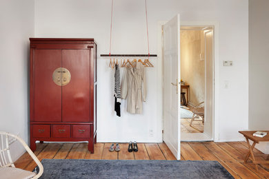 This is an example of a medium sized world-inspired wardrobe in Berlin with light hardwood flooring.