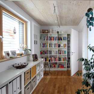Mittelgroßes Modernes Lesezimmer mit weißer Wandfarbe, braunem Holzboden und braunem Boden in München