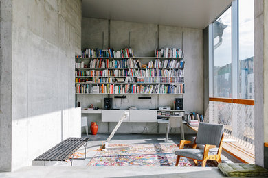 Cette photo montre un bureau industriel de taille moyenne avec un mur gris, sol en béton ciré, aucune cheminée et un bureau intégré.