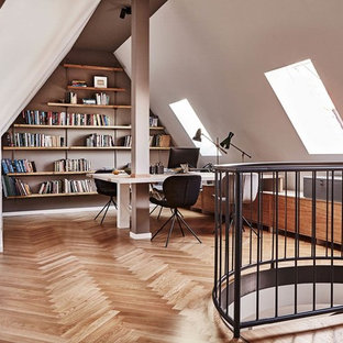 Großes Nordisches Arbeitszimmer ohne Kamin mit Arbeitsplatz, weißer Wandfarbe, braunem Holzboden, freistehendem Schreibtisch und braunem Boden in Berlin