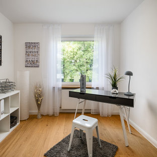 Mittelgroßes Klassisches Arbeitszimmer mit Arbeitsplatz, weißer Wandfarbe, braunem Holzboden, freistehendem Schreibtisch und braunem Boden in München