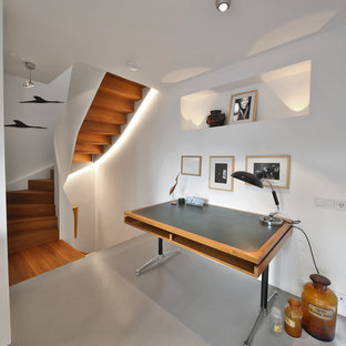 Mittelgroßes Modernes Arbeitszimmer ohne Kamin mit Arbeitsplatz, weißer Wandfarbe, Betonboden, freistehendem Schreibtisch und grauem Boden in München