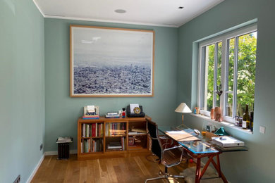 Mittelgroßes Modernes Arbeitszimmer mit Arbeitsplatz, blauer Wandfarbe, hellem Holzboden und freistehendem Schreibtisch in Sonstige