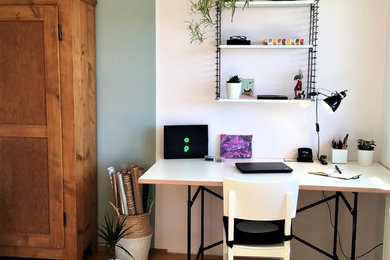 Kleines Modernes Arbeitszimmer ohne Kamin mit Arbeitsplatz, braunem Holzboden, freistehendem Schreibtisch, braunem Boden und bunten Wänden in München