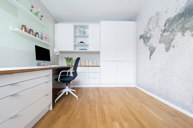 Mittelgroßes Skandinavisches Arbeitszimmer ohne Kamin mit Arbeitsplatz, beiger Wandfarbe, braunem Holzboden, Einbau-Schreibtisch und braunem Boden in Berlin