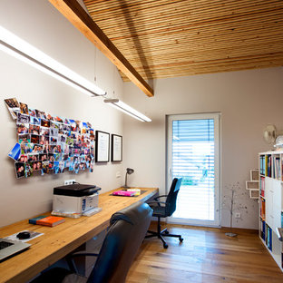 Mittelgroßes Landhausstil Arbeitszimmer ohne Kamin mit Arbeitsplatz, weißer Wandfarbe, braunem Holzboden, Einbau-Schreibtisch und braunem Boden in Nürnberg
