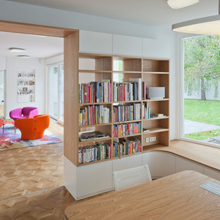 Mittelgroßes Modernes Lesezimmer ohne Kamin mit weißer Wandfarbe, braunem Holzboden, freistehendem Schreibtisch und braunem Boden in Berlin