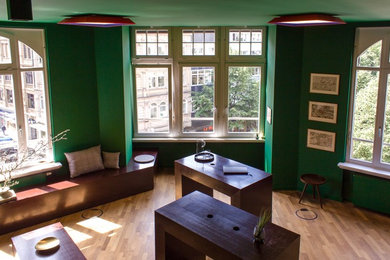 Mittelgroßes Modernes Arbeitszimmer mit Arbeitsplatz, grüner Wandfarbe, braunem Holzboden und braunem Boden in Frankfurt am Main