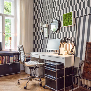 Mittelgroßes Modernes Arbeitszimmer mit Arbeitsplatz, bunten Wänden, braunem Holzboden, braunem Boden und freistehendem Schreibtisch in München