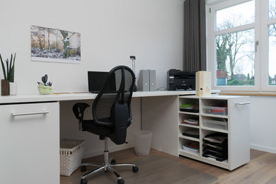 Mittelgroßes Modernes Arbeitszimmer ohne Kamin mit Arbeitsplatz, braunem Boden, weißer Wandfarbe, braunem Holzboden und Einbau-Schreibtisch in Hamburg