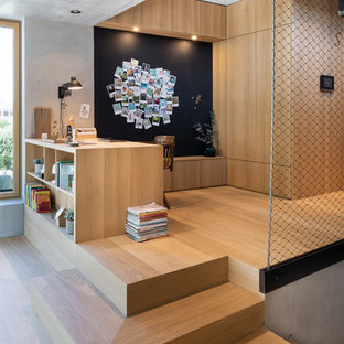 Nordisches Arbeitszimmer ohne Kamin mit Arbeitsplatz, hellem Holzboden, Einbau-Schreibtisch, grauer Wandfarbe, beigem Boden und Holzwänden in München