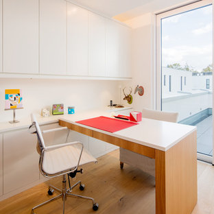 Mittelgroßes Modernes Arbeitszimmer ohne Kamin mit Arbeitsplatz, weißer Wandfarbe, braunem Holzboden, Einbau-Schreibtisch und beigem Boden in Düsseldorf
