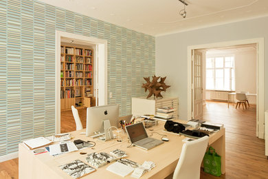 Großes Modernes Arbeitszimmer ohne Kamin mit Arbeitsplatz, bunten Wänden, braunem Holzboden und freistehendem Schreibtisch in Berlin