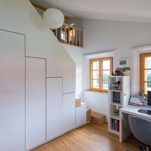 Landhaus Arbeitszimmer mit weißer Wandfarbe, braunem Holzboden, freistehendem Schreibtisch, braunem Boden und gewölbter Decke in München