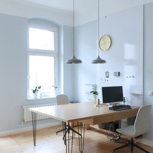 Großes Skandinavisches Arbeitszimmer ohne Kamin mit Arbeitsplatz, blauer Wandfarbe, hellem Holzboden, Einbau-Schreibtisch und beigem Boden in Berlin