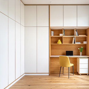 Modernes Arbeitszimmer mit Arbeitsplatz, hellem Holzboden, Einbau-Schreibtisch, weißer Wandfarbe und beigem Boden in Berlin