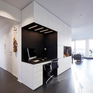 Mittelgroßes Modernes Arbeitszimmer ohne Kamin mit Arbeitsplatz, weißer Wandfarbe, Einbau-Schreibtisch und schwarzem Boden in Frankfurt am Main