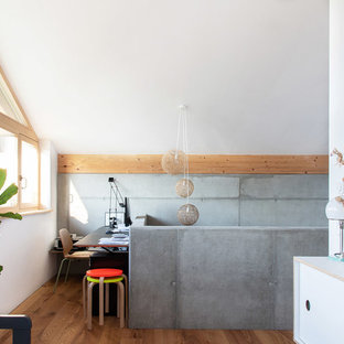 Nordisches Arbeitszimmer mit weißer Wandfarbe, braunem Holzboden, freistehendem Schreibtisch und braunem Boden in München