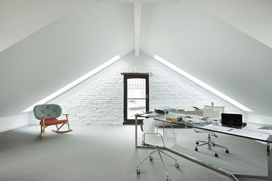 Geräumiges Industrial Arbeitszimmer ohne Kamin mit Arbeitsplatz, weißer Wandfarbe, Teppichboden und freistehendem Schreibtisch in Frankfurt am Main