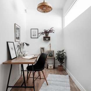 Idéer för minimalistiska hemmabibliotek, med vita väggar, mellanmörkt trägolv, ett fristående skrivbord och beiget golv