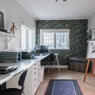 Modern inredning av ett mellanstort hemmabibliotek, med flerfärgade väggar, ljust trägolv och ett inbyggt skrivbord
