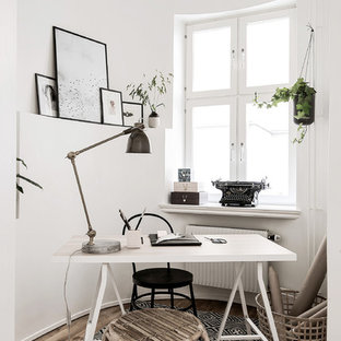 Nordisk inredning av ett arbetsrum, med vita väggar, mellanmörkt trägolv, ett fristående skrivbord och brunt golv