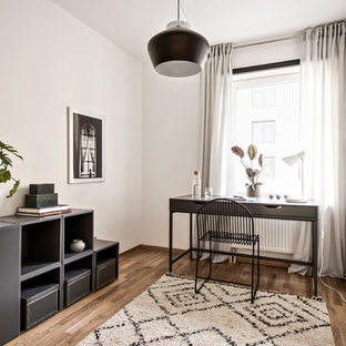 Inredning av ett skandinaviskt hemmabibliotek, med vita väggar, mellanmörkt trägolv, ett fristående skrivbord och brunt golv