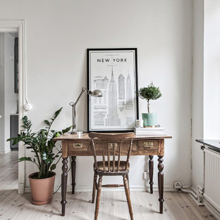 Idéer för ett litet minimalistiskt hemmabibliotek, med vita väggar, ljust trägolv, ett fristående skrivbord och beiget golv