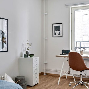 Minimalistisk inredning av ett arbetsrum, med vita väggar, mellanmörkt trägolv, ett fristående skrivbord och brunt golv