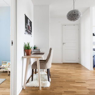 Foto på ett skandinaviskt arbetsrum, med mellanmörkt trägolv, ett fristående skrivbord och brunt golv