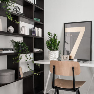 Minimalistisk inredning av ett hemmabibliotek, med vita väggar, mörkt trägolv, ett fristående skrivbord och svart golv