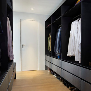 Esempio di una cabina armadio per uomo design con ante lisce, ante nere, parquet chiaro e pavimento beige