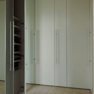 Foto di un'ampia cabina armadio unisex moderna con ante lisce, ante bianche, parquet chiaro e pavimento bianco