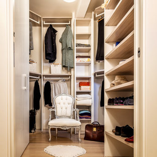 Idée de décoration pour un dressing design de taille moyenne et neutre avec un placard sans porte, des portes de placard beiges, sol en stratifié et un sol marron.