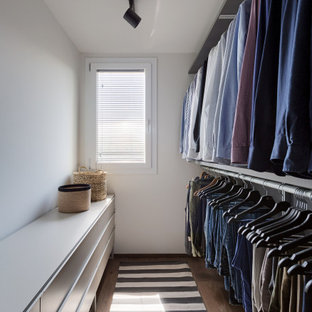 Ispirazione per una cabina armadio unisex design di medie dimensioni con ante lisce, ante grigie, pavimento in legno massello medio e pavimento marrone