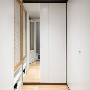 Idee per una cabina armadio unisex scandinava di medie dimensioni con ante lisce, ante bianche, parquet chiaro e soffitto ribassato