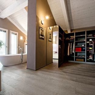 Foto di una cabina armadio unisex design con nessun'anta, ante grigie, pavimento in legno massello medio e pavimento marrone
