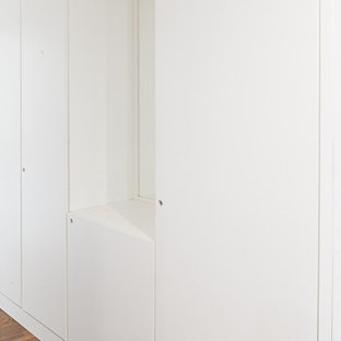 Ejemplo de armario y vestidor unisex, contemporáneo, grande, con armarios con rebordes decorativos, puertas de armario blancas y suelo de madera clara