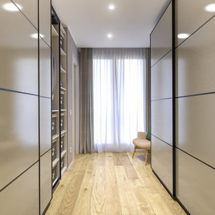 Modelo de armario vestidor unisex, escandinavo, de tamaño medio, con armarios con paneles lisos, puertas de armario beige y suelo de madera clara